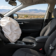 Defective airbag car accident in Albuquerque, with a deployed airbag and seat belt visible inside a vehicle