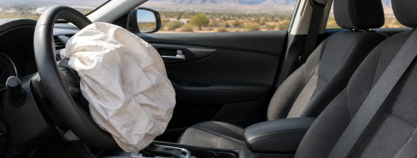 Defective airbag car accident in Albuquerque, with a deployed airbag and seat belt visible inside a vehicle